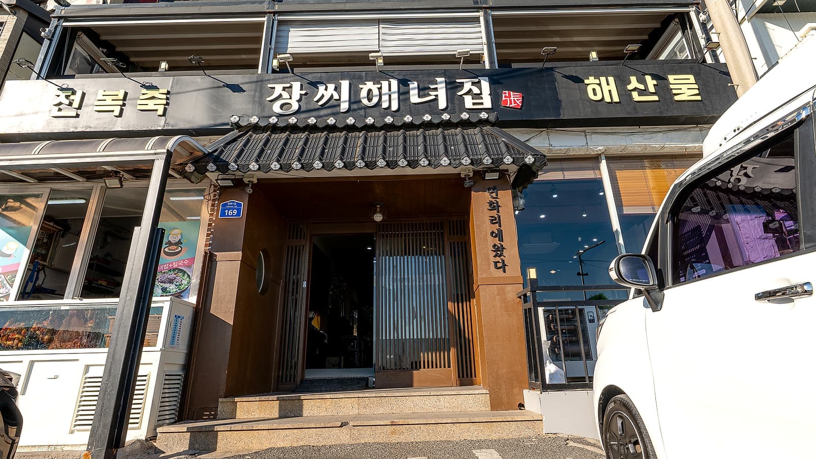 버스에서 내려 걸어오면 만나는 장씨해녀집 정면 외관과 매장 앞 도로